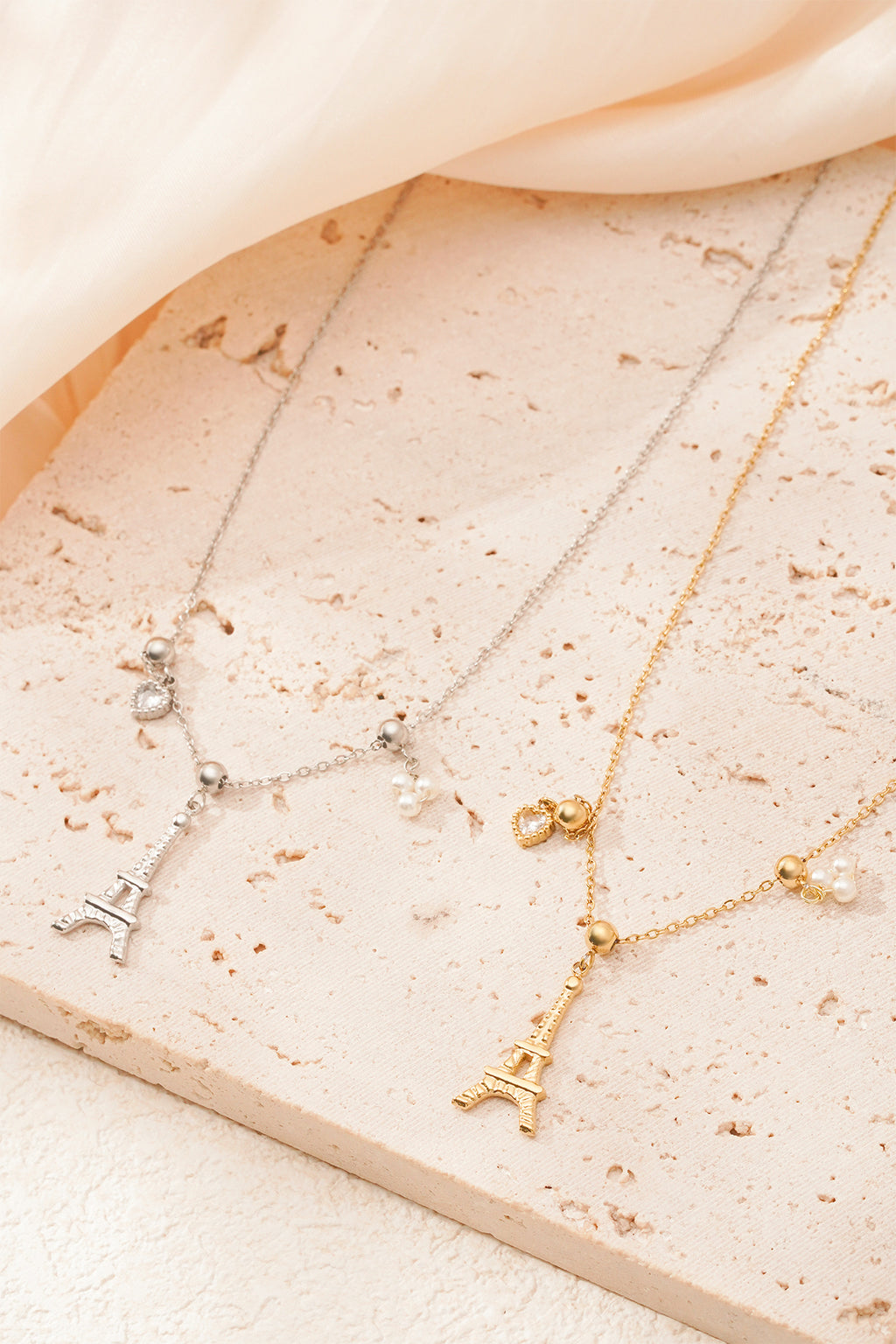Eiffeltoren ketting - goud en zilver - neergelegd op een decoratieve stenen plaat