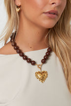 Ketting met grote kralen en sluiting aan de voorkant – 15 mm - Bruin - gedragen om de hals van een model