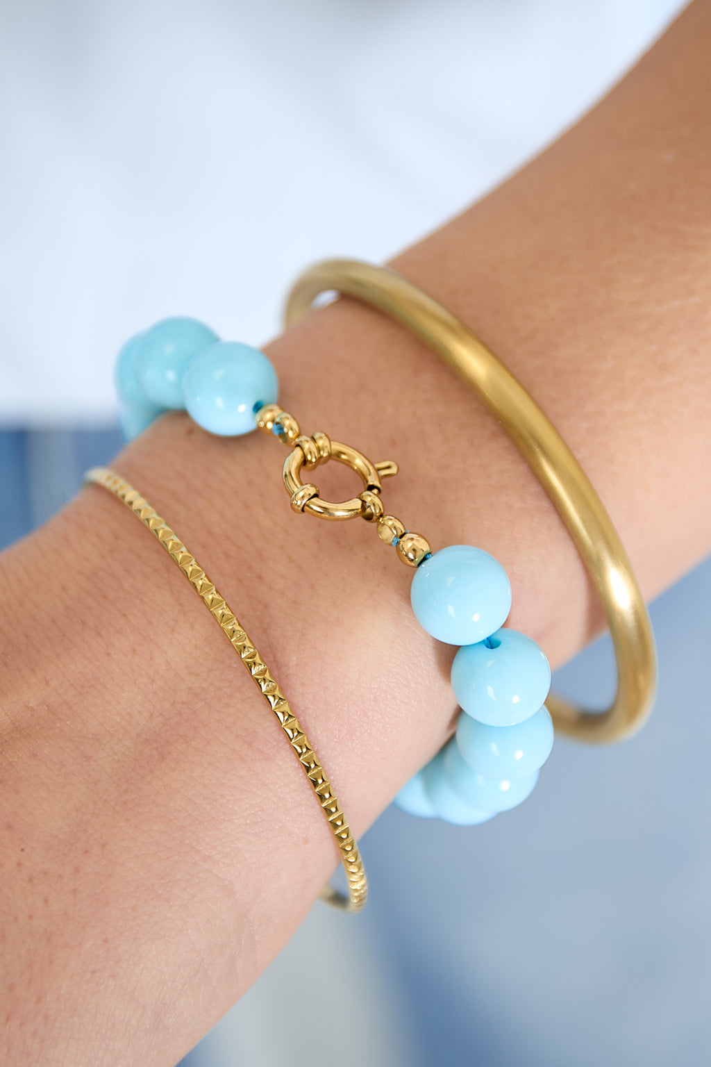 Armband met middelgrote kralen en sluiting aan de voorkant – 12 mm - licht blauw - gedragen om de arm van een model