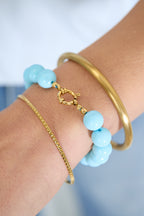 Armband met middelgrote kralen en sluiting aan de voorkant – 12 mm - licht blauw - gedragen om de arm van een model