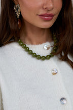 Ketting met grote kralen en sluiting aan de voorkant – 15 mm - donker groen - gedragen om de hals van een model