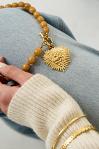 Kralenketting met frontsluitingcharm - kaki - neergelegd over een spijkerbroek