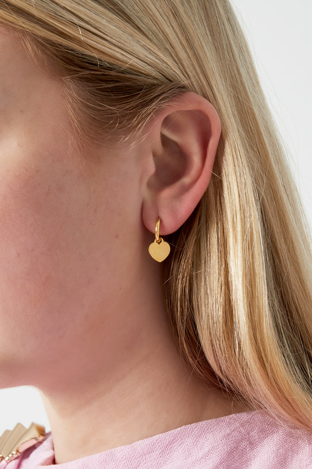 Eenvoudige hartoorbellen - goud - gedragen in het oor van een model