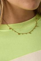 Ketting met afwisselende bolletjes - goud - gedragen om de hals van een model ingezoomd