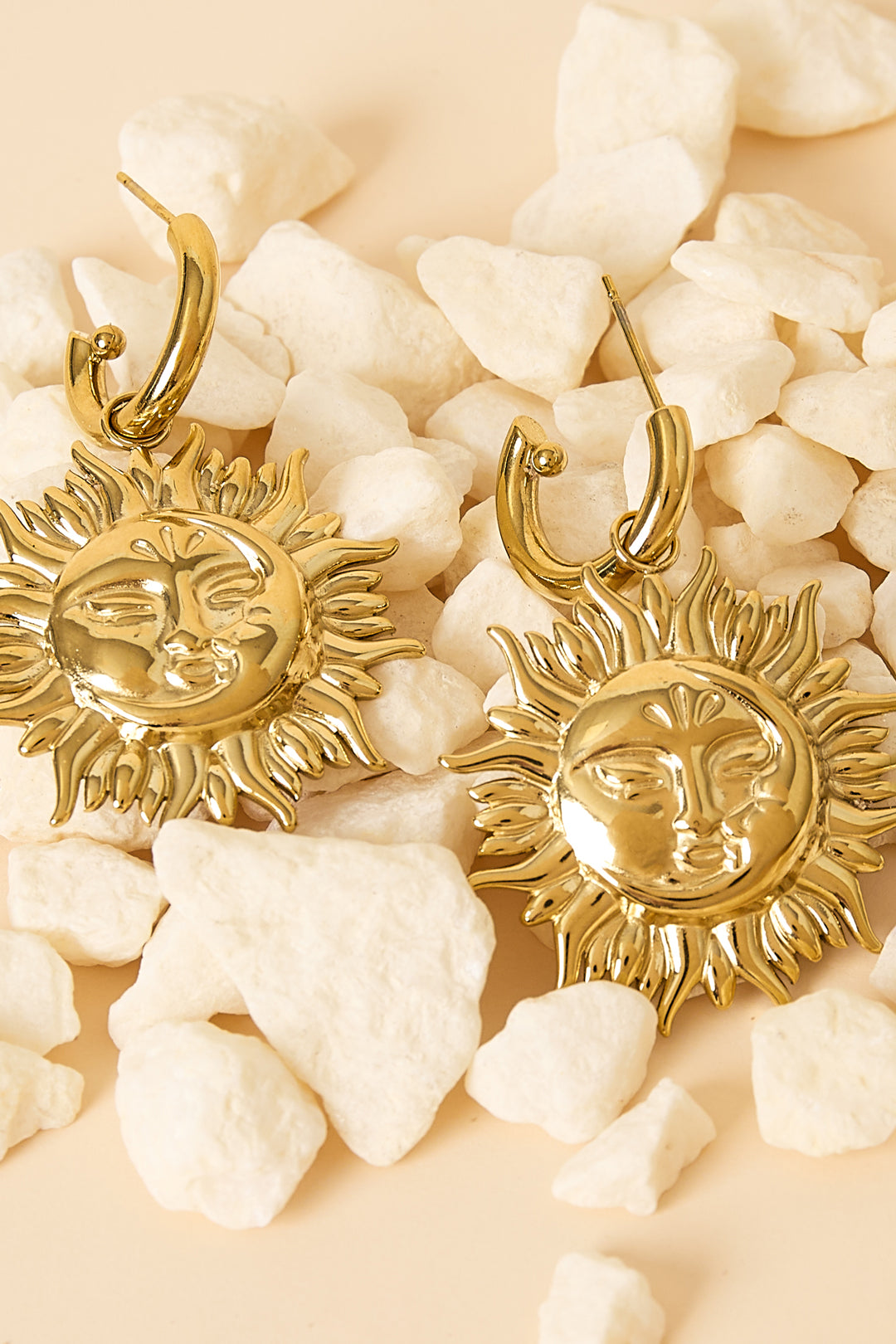 Oorbellen van roestvrij staal, zon, goud, neergelegd op stenen