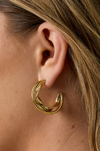 Dubbele dikke oorringen met gedraaide details - goud - gedragen in het oor van een model ingezoomd