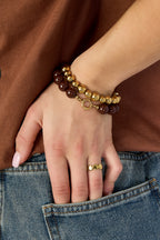 Armband met middelgrote kralen en sluiting aan de voorkant – 12 mm - bruin - gedragen om de arm van een model