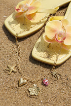 Ketting met grote schakels en charms - neergelegd op het strand met slippers