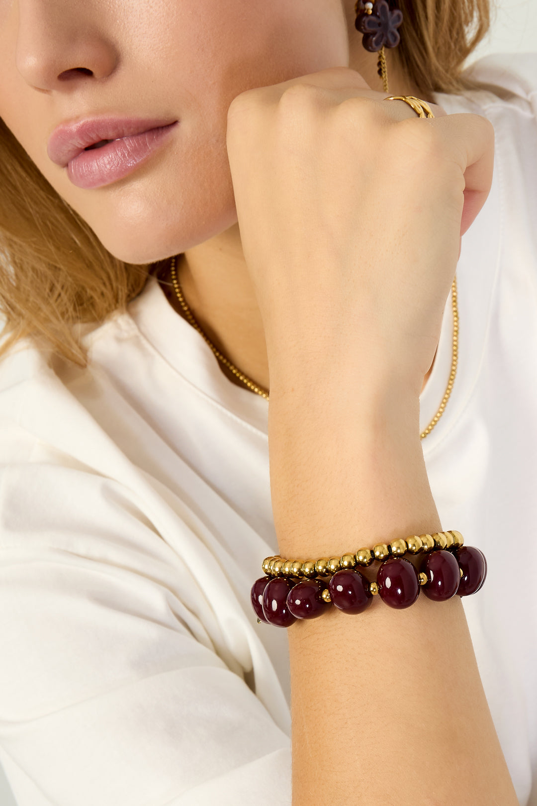 Elastieke kralenarmband met grote kralen - wijn rood - gedragen om de arm van een model